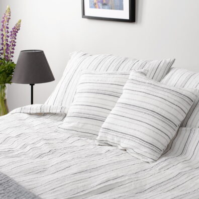 Linge de lit en lin lave sur le find blanc cassé en rayures fines grises et bleu gris.