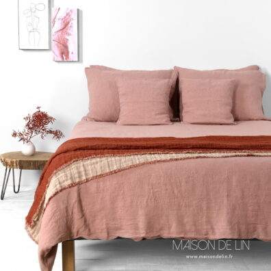 Linge de lit rose vieux en lin lavé composée de housse de couette, de taie d'oreille et de drap.